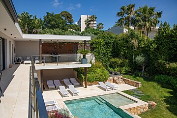 A large house with a swimming pool and lounge chairs