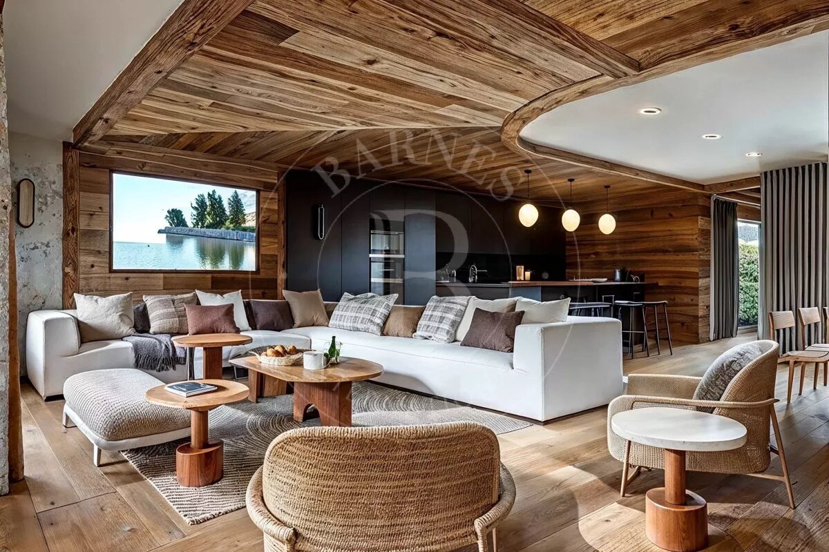 Cozy, modern chalet living room with curved wood ceilings, a large white sectional sofa, woven armchairs, and scenic lake views.