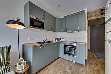A kitchen with grey cabinets and a stove top oven