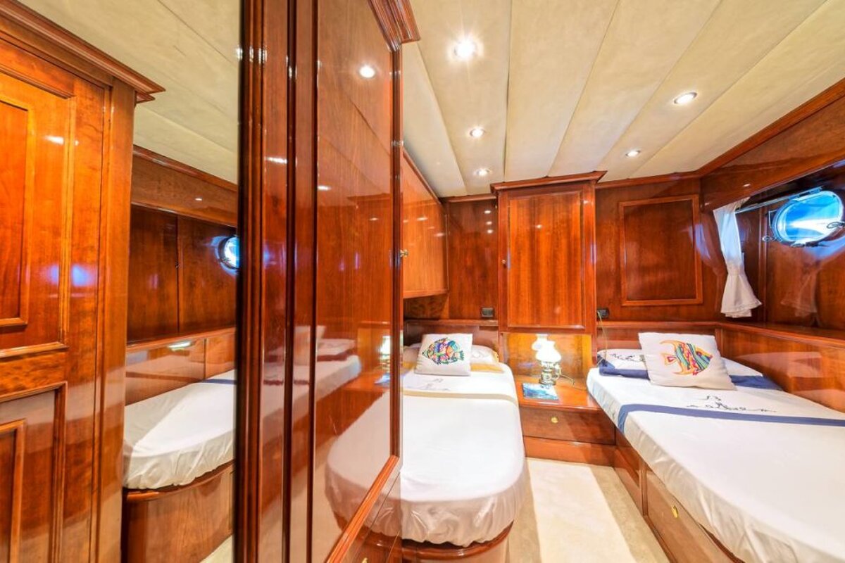 A bedroom on a boat with two beds and a mirror