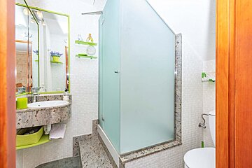 A bathroom with a sink and toilet and a glass shower