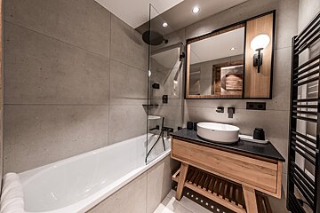 A bathroom with a bathtub sink and mirror