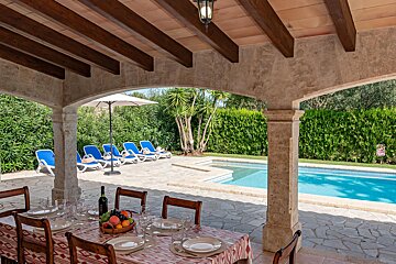A table with plates and a bottle of wine sits in front of a pool