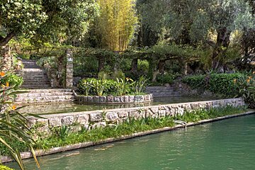 A stone wall surrounds a pond in a garden