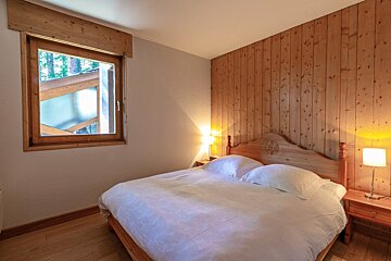 A bedroom with a striped bed and a teddy bear on the dresser