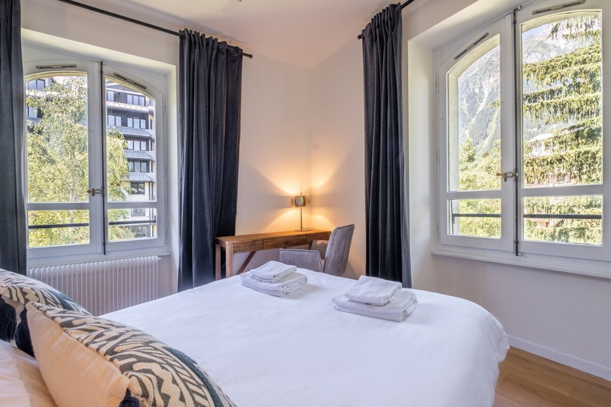 A bedroom with a large bed and two windows