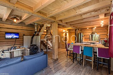 A living room in a log cabin with a flat screen tv