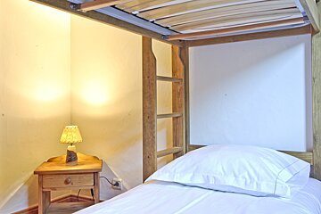 A bedroom with a bunk bed and a nightstand with a lamp on it