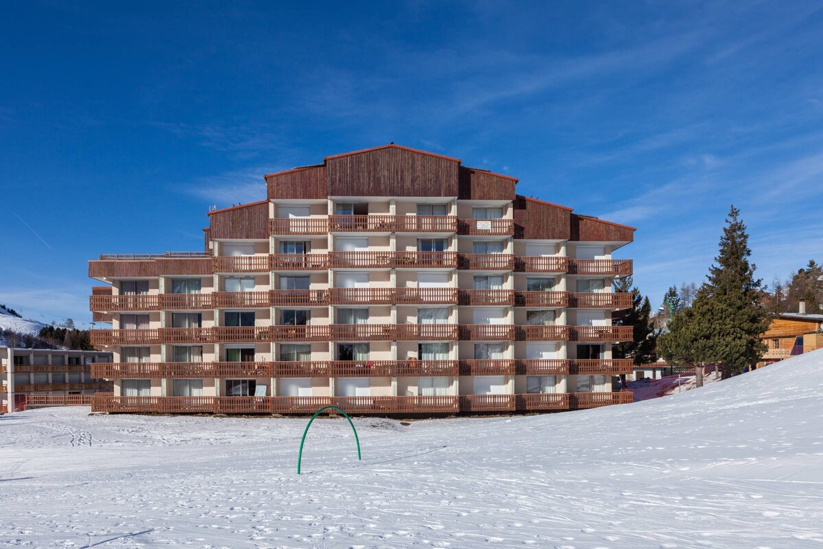 A large building with a lot of balconies is surrounded by snow