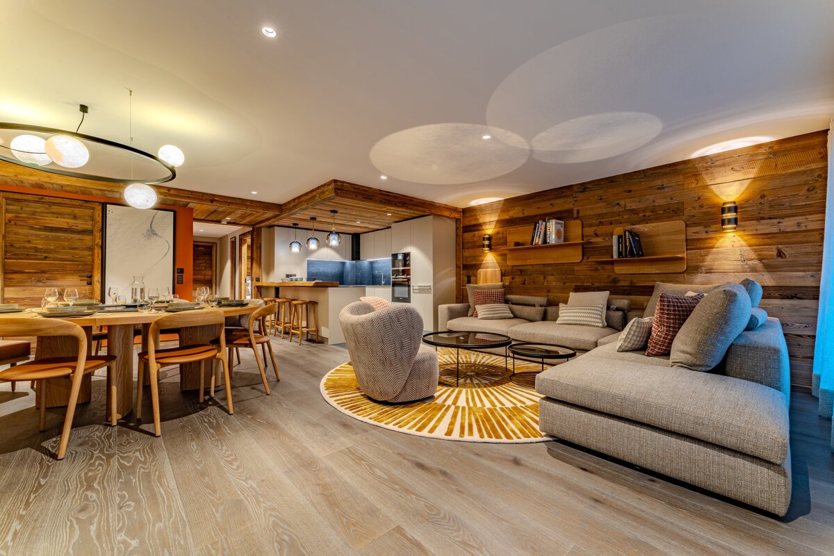 Cozy, modern chalet interior featuring a wood-paneled living room with a grey sectional and an adjacent dining area.