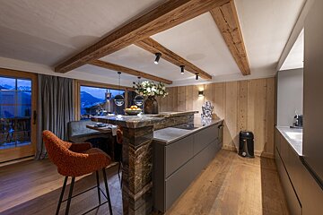 A kitchen with a marble counter top and wood paneling