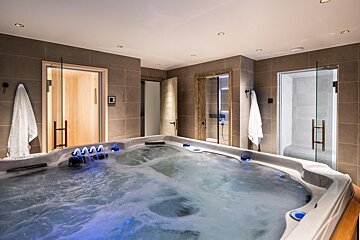 A large hot tub is in a bathroom next to a sauna
