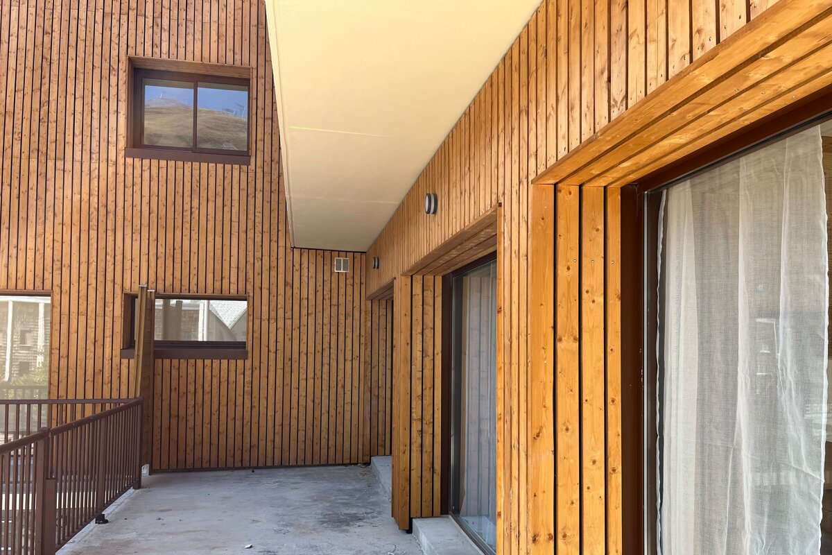 A wooden building with a balcony and sliding glass doors