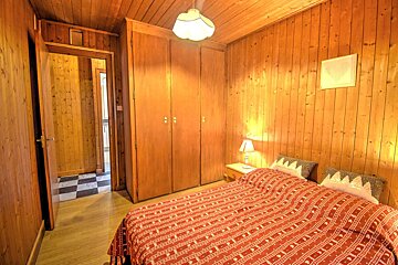 A bedroom with wood paneling and a bed