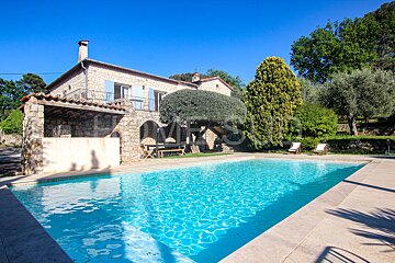 A large swimming pool is in front of a stone house