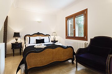A bedroom with a wicker bed and a purple chair