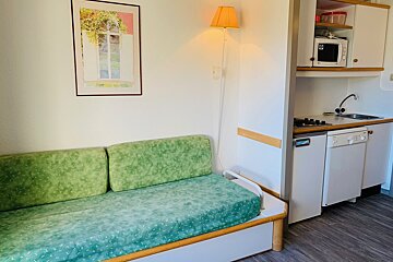 A kitchen with a green couch and a microwave
