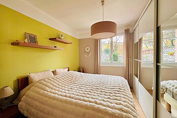 Bright bedroom featuring a fluffy bed, lime green wall with shelves, window with garden view, and mirrored closet.