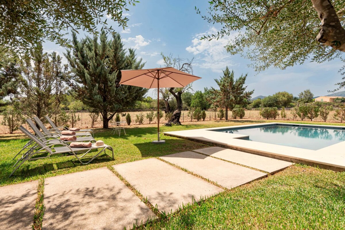 A swimming pool surrounded by lawn chairs and an umbrella