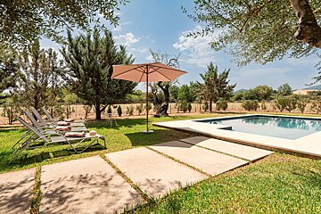 A swimming pool surrounded by lawn chairs and an umbrella