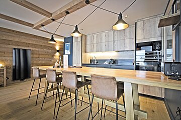 A kitchen with a long wooden table and stools