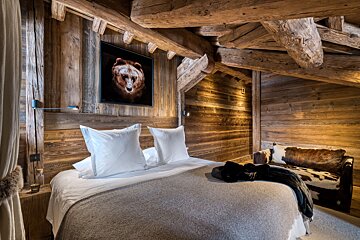 A bedroom with a picture of a bear on the wall above the bed