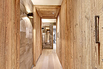 A hallway with wood paneling and a mirror on the wall