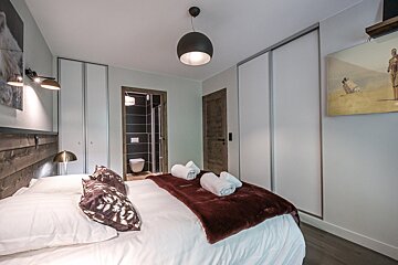 A bedroom with a painting on the wall above the bed