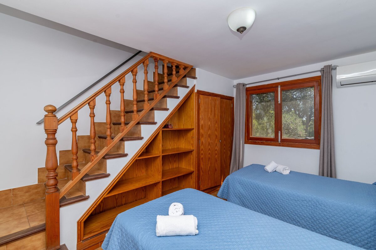 A bedroom with two beds and stairs leading up to the second floor