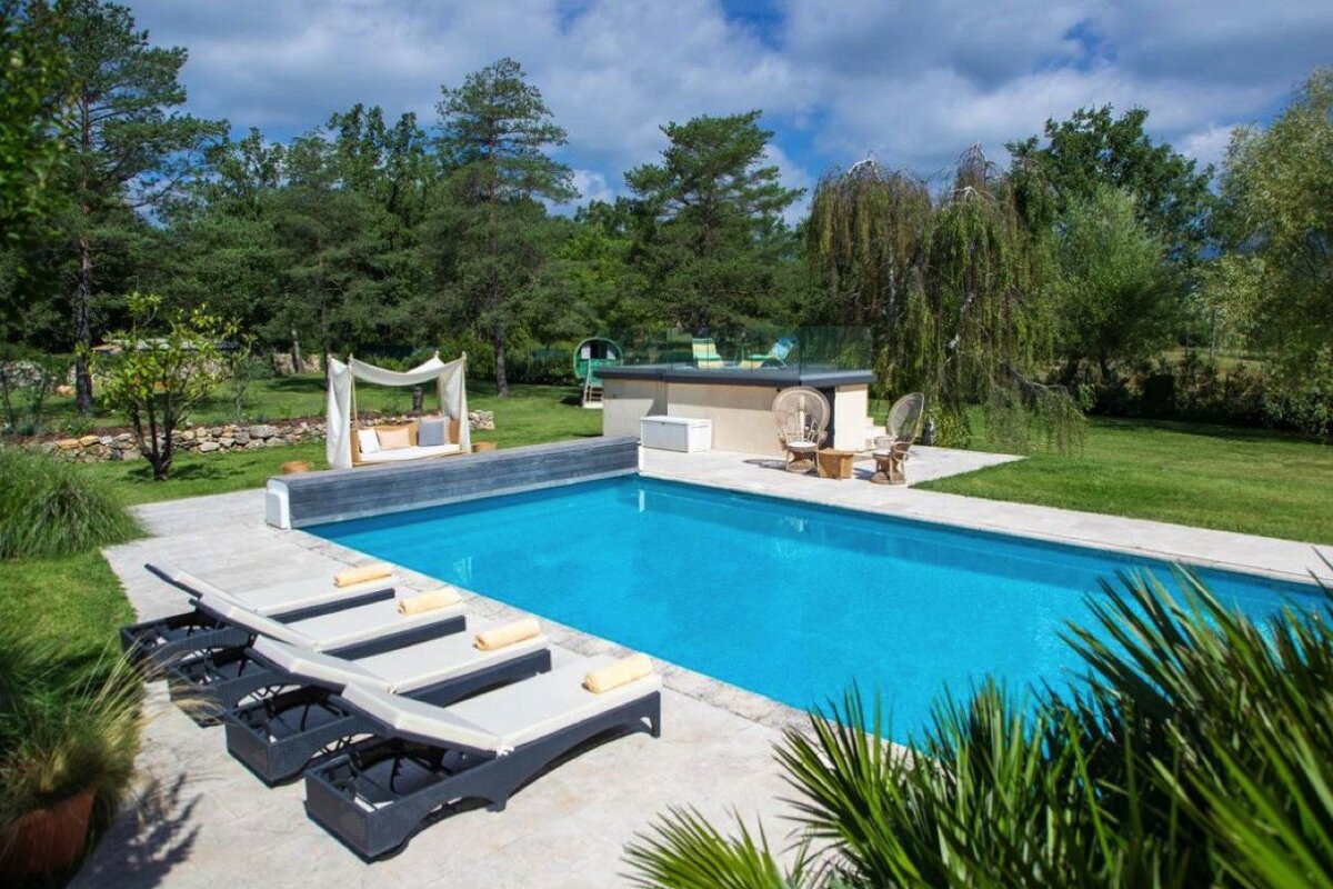 A large swimming pool surrounded by chairs and trees