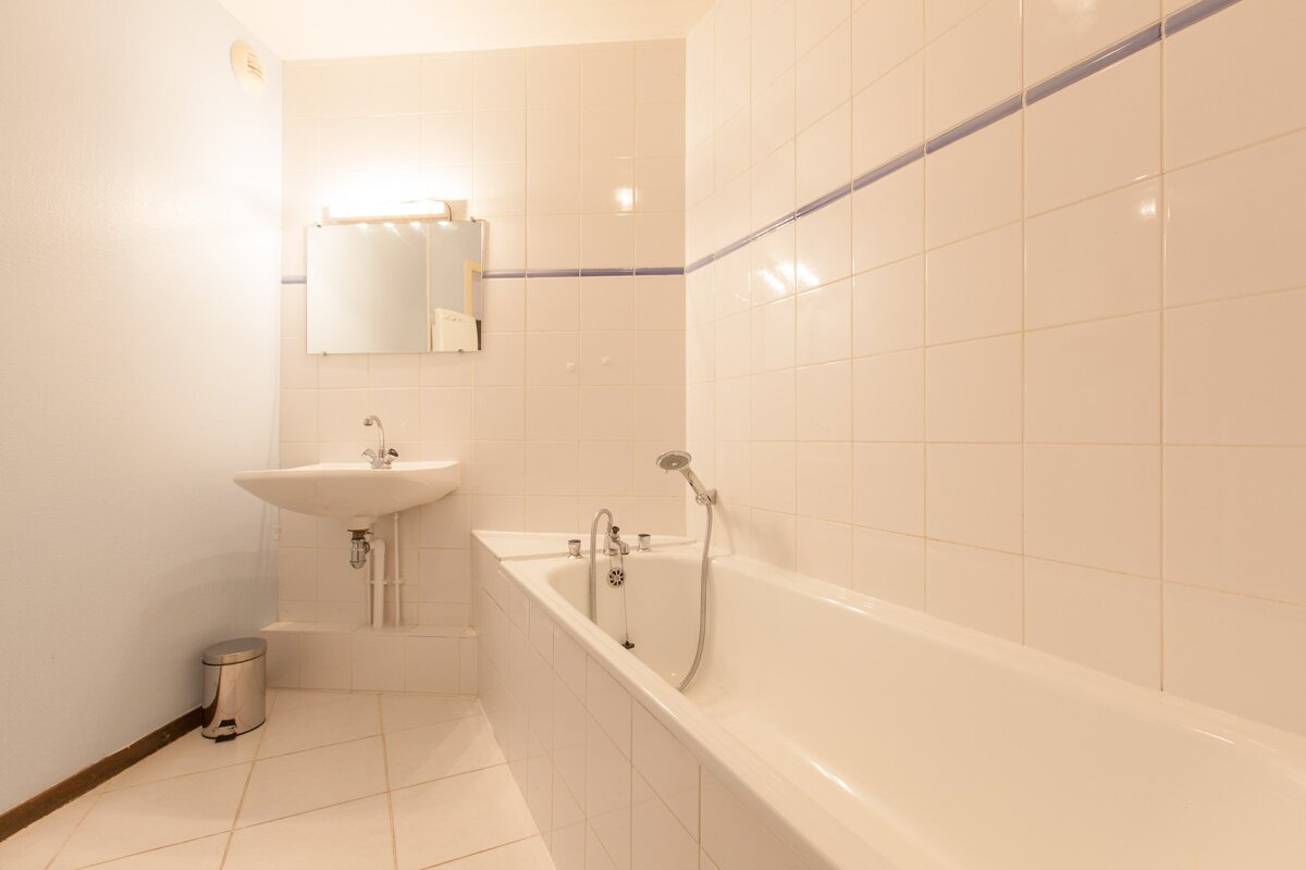 A bathroom with white tiles and a sink and bathtub