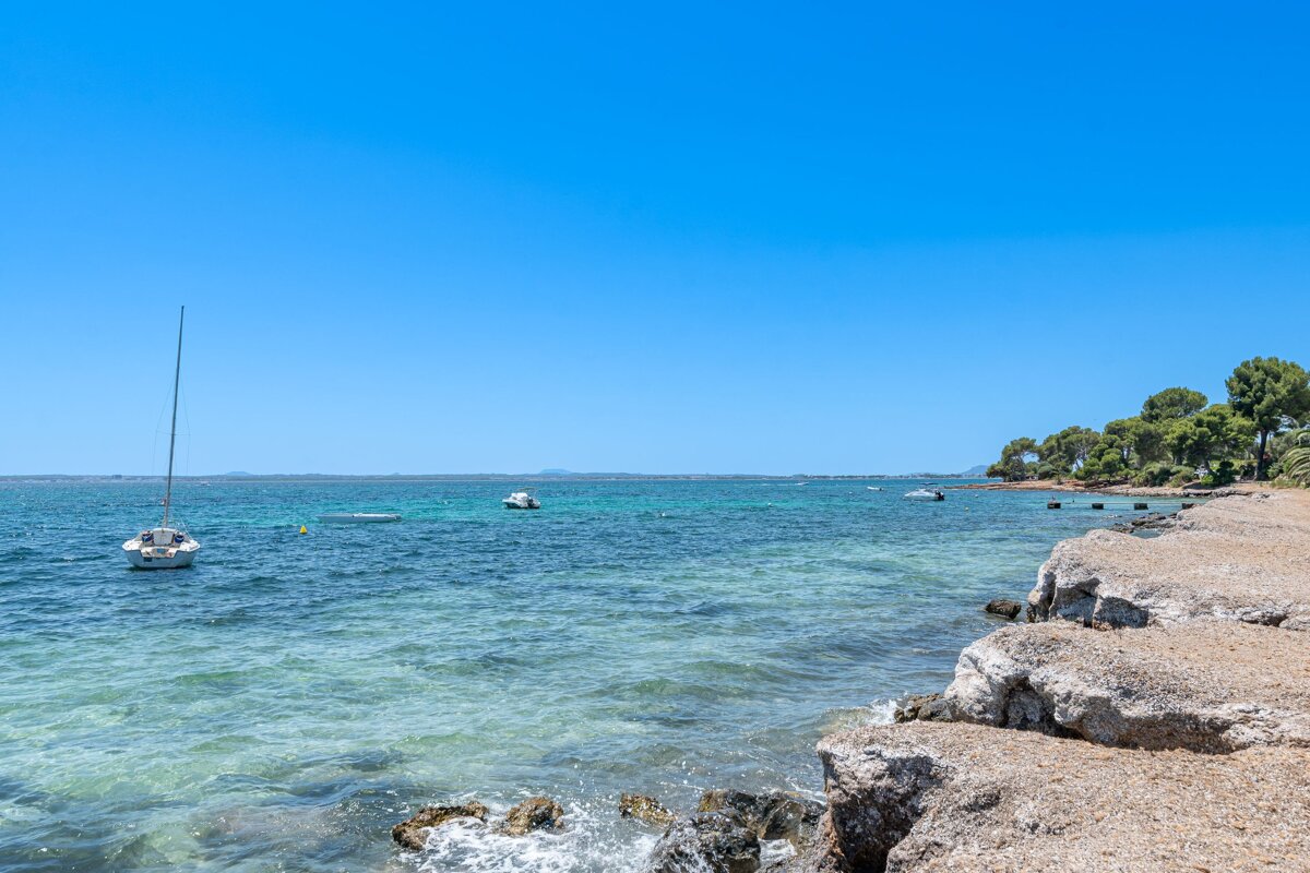 A few boats are in the water near a rocky shoreline