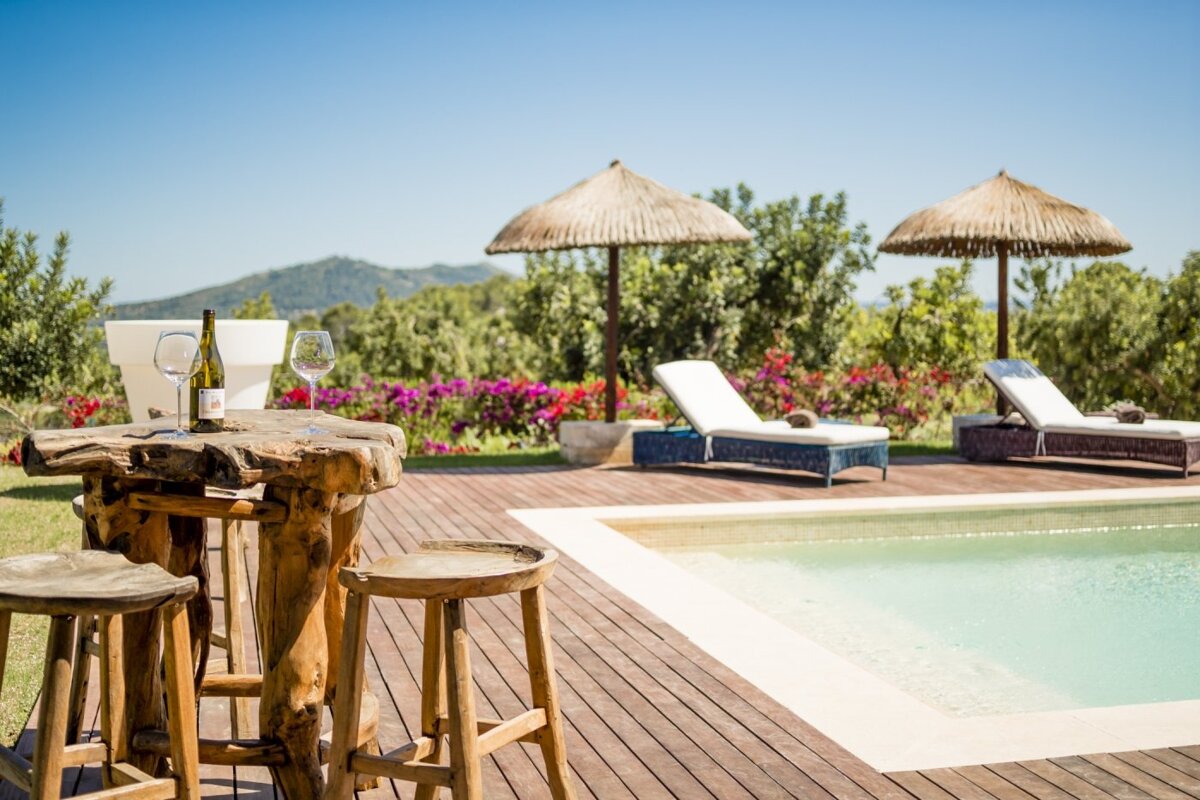 A bottle of wine sits on a wooden table next to a pool