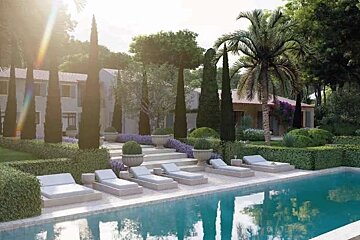 An artist 's impression of a swimming pool with lounge chairs and a house in the background