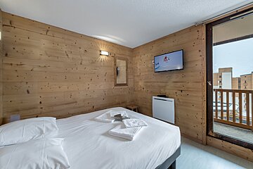 A hotel room with a bed and a flat screen tv