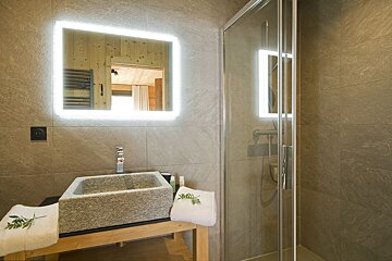 A bathroom with a stone sink and a shower