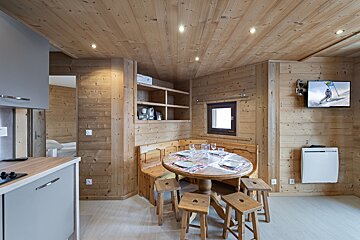 A kitchen with a table and stools and a flat screen tv
