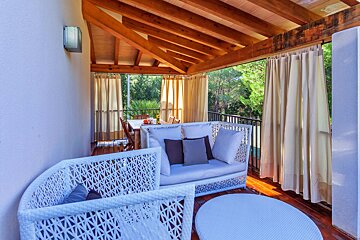 A balcony with a couch and chairs under a wooden roof