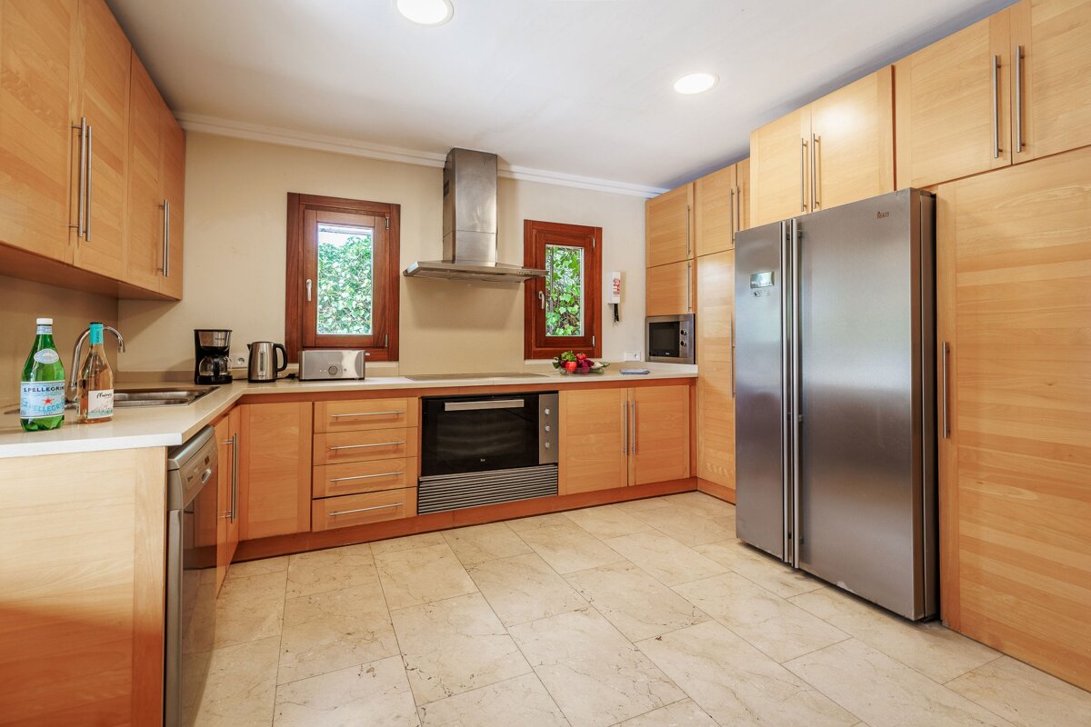 A kitchen with wooden cabinets and a stainless steel refrigerator