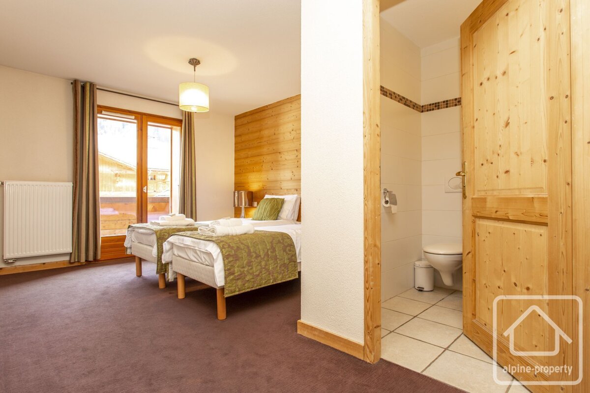 A bedroom with two beds next to a toilet and a sign that says alpine property
