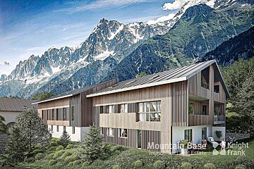 A modern wooden building with large windows sits nestled in a lush green landscape, backed by towering snow-capped mountains.