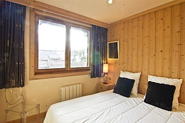 A bedroom with a bed a nightstand and a window