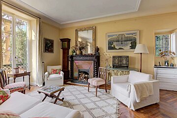 A living room with two white chairs and a fireplace