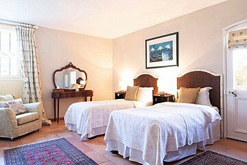 A bedroom with two beds a chair and a mirror