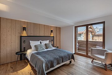 A bedroom with a large bed and a chair