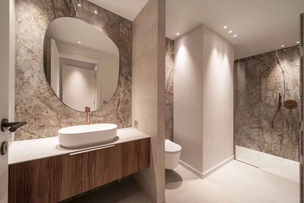 A bathroom with a round mirror and a sink