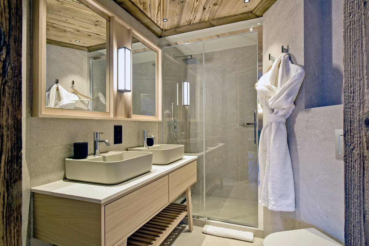 A bathroom with two sinks and a walk in shower