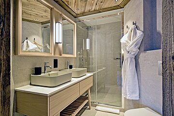 A bathroom with two sinks and a walk in shower