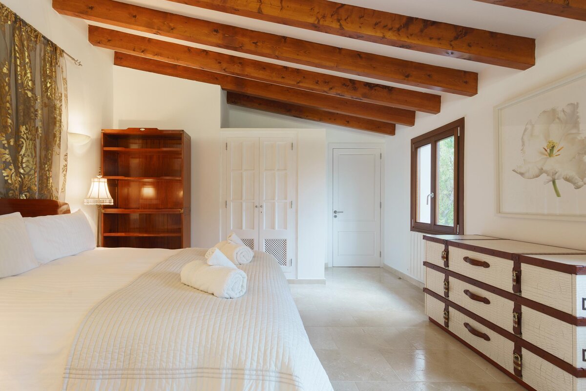 A bedroom with wooden beams and a picture of a flower on the wall