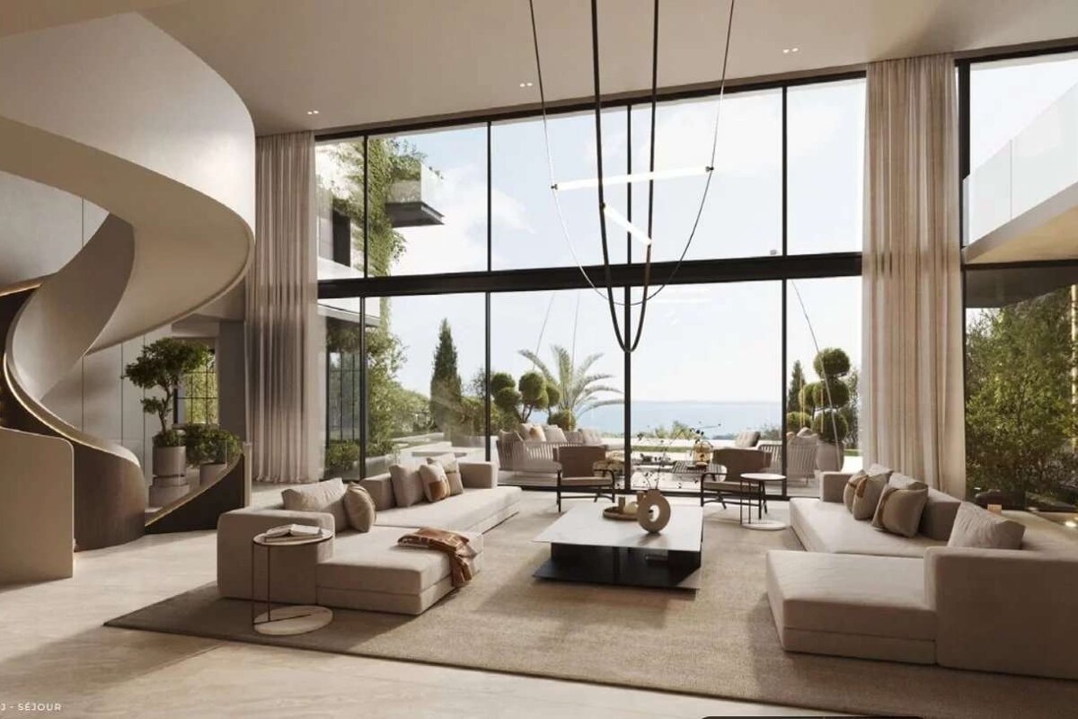 Luxurious modern living room with floor-to-ceiling windows showcasing an ocean view, an elegant spiral staircase, and neutral-toned furniture.